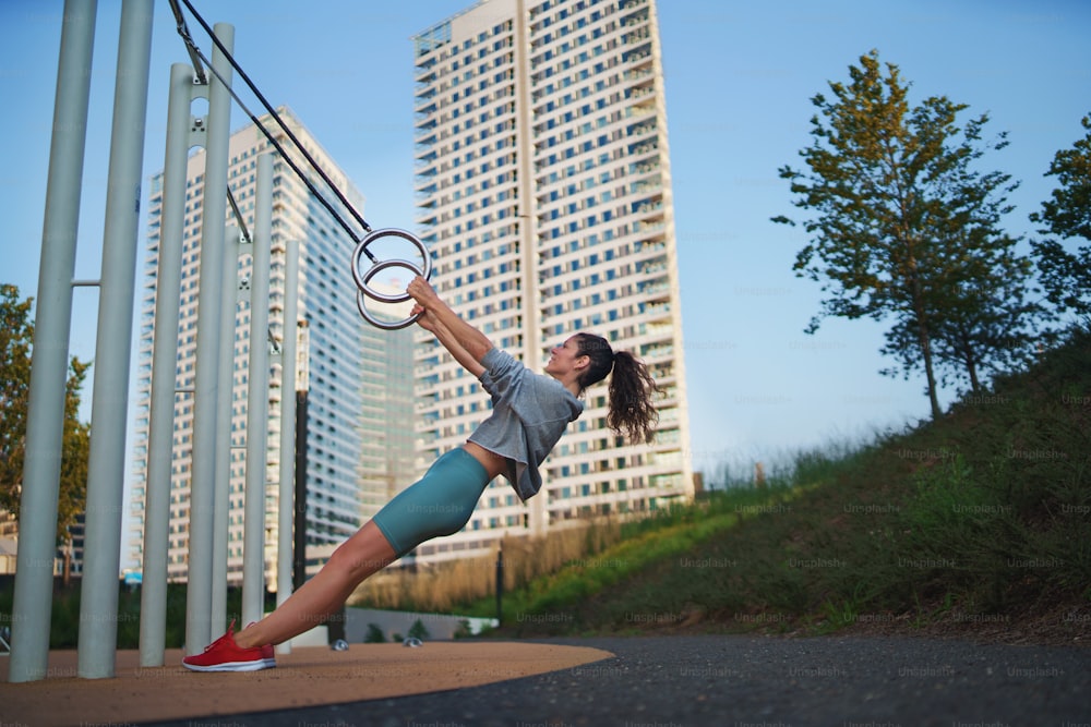Donna adulta media che fa esercizio su un tappetino all'aperto in città, concetto di stile di vita sano.