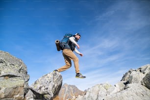 Mature man with backpack hiking in mountains in summer. Copy space.