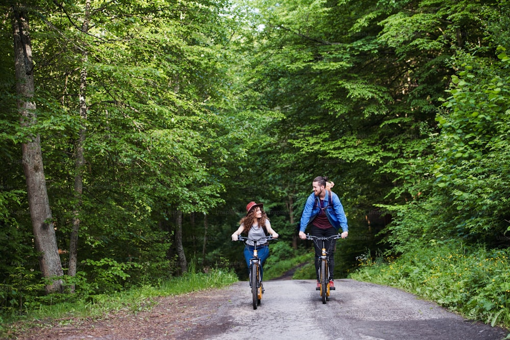 Jovens turistas casal viajantes com mochilas e scooters elétricas na natureza.