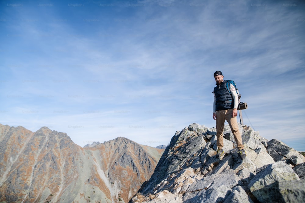 Mature man with backpack hiking in mountains in summer. Copy space.