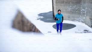 Front view of active senior woman running outdoors in winter, doing exercise.