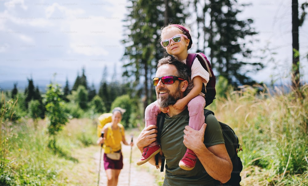 Front view of family with small child hiking outdoors in summer nature.