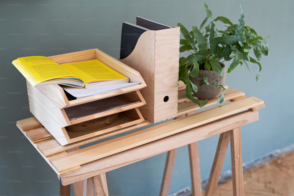 Paper and document wooden tray holders and organisers on desk with plant, natural decor concept.