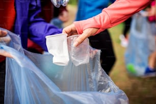Una sección media de un grupo de jóvenes en forma recogiendo basura en la naturaleza, un concepto de plogging.
