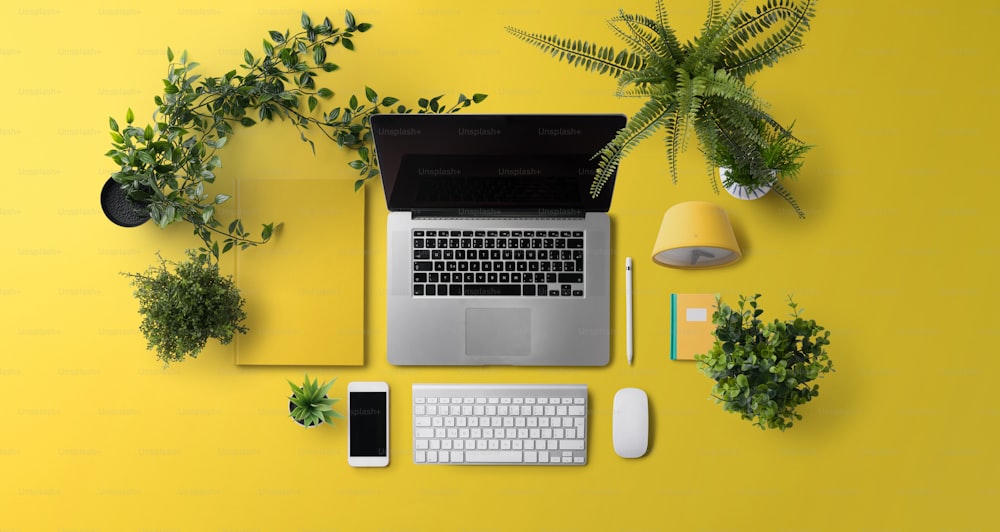 Flat lay top view office desk working space with laptop, tablet, smartphone on yellow background.