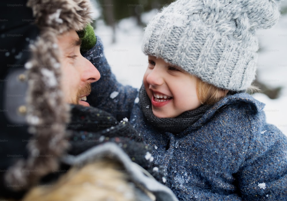 Close-up portrait of father with small son in snowy winter nature, talking in.