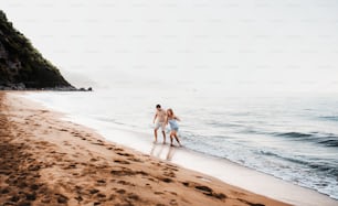 Um homem e uma mulher alegres andando na praia nas férias de verão, de mãos dadas. Espaço de cópia.