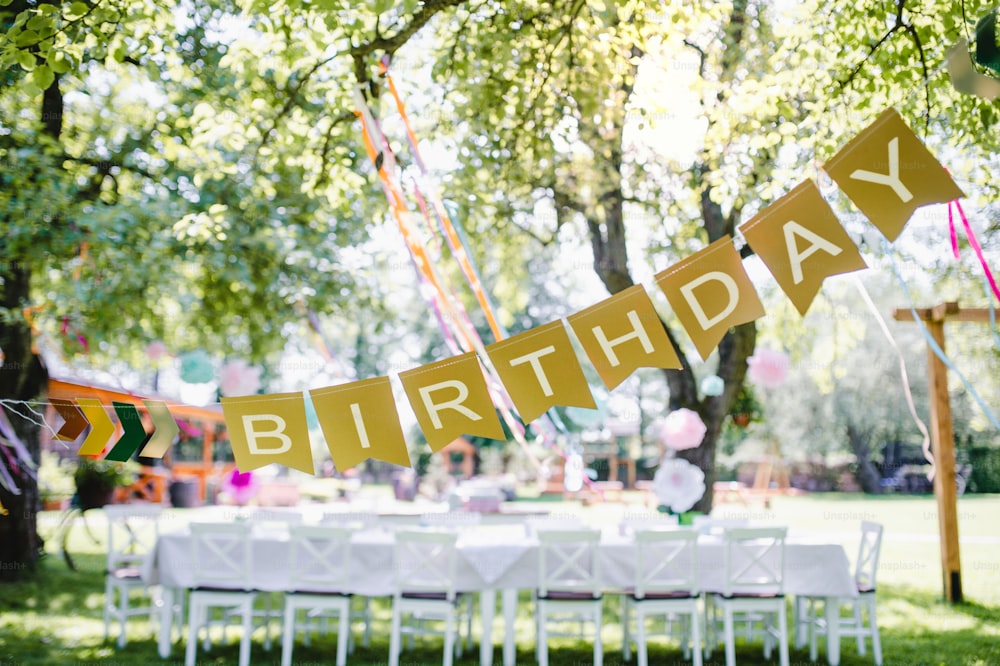 Uma mesa posta para a festa de aniversário das crianças ao ar livre no jardim no verão, conceito de celebração.
