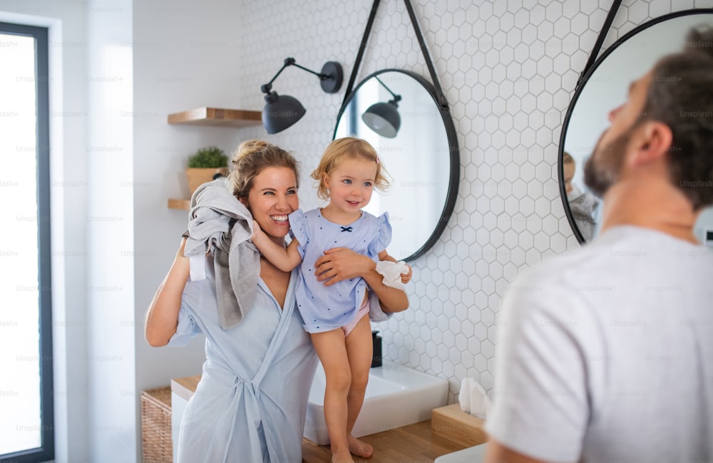 Eine junge Familie mit kleiner Tochter drinnen im Badezimmer, im Gespräch.