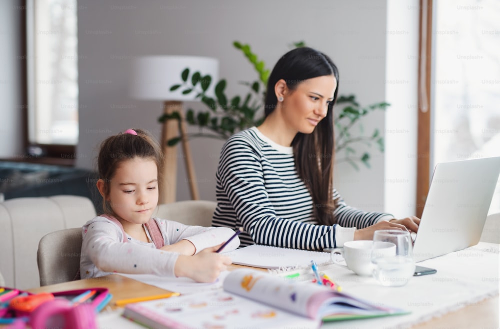 Mother with school girl indoors at home, distance learning and home office concept.