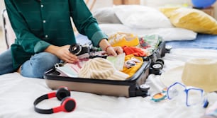 Unrecognizable young woman with suitcase packing for holiday at home, coronavirus concept.