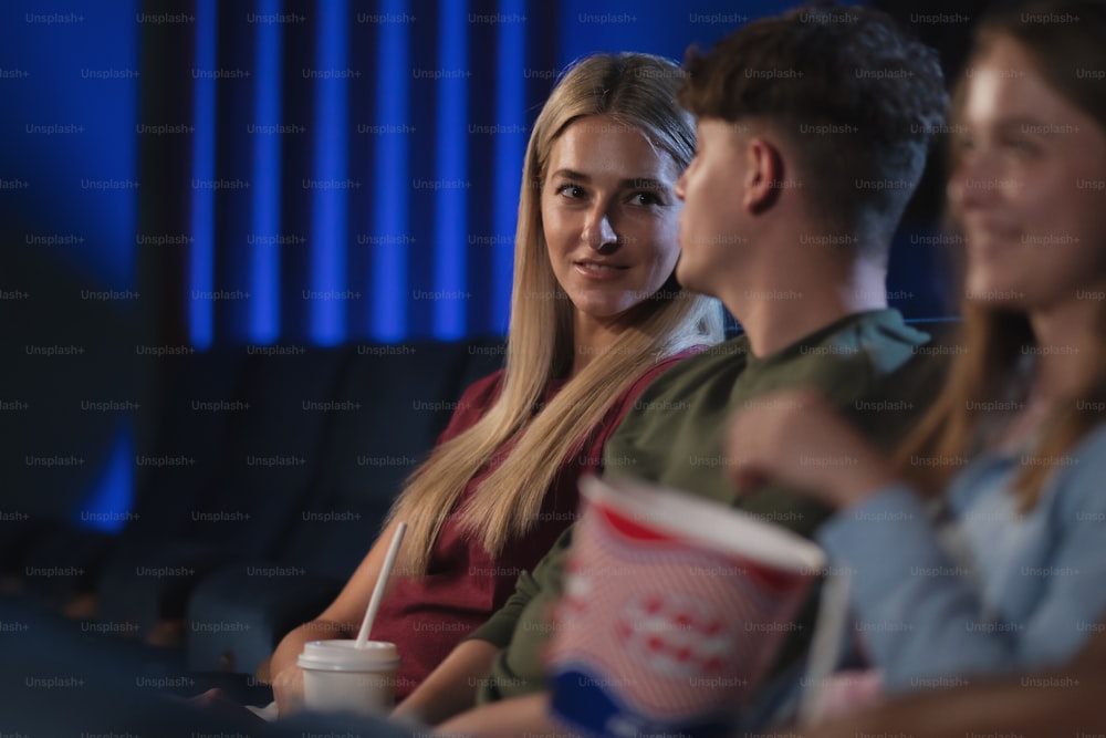 A happy young couple watching film in the cinema, talking.