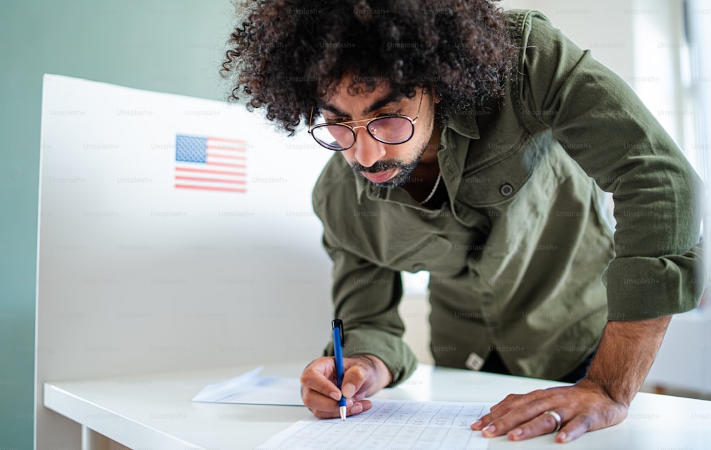 Man voter in polling place, usa elections concept, writing.