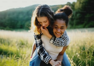 Front view of cheerful young teenager girls friends outdoors in nature, having fun.