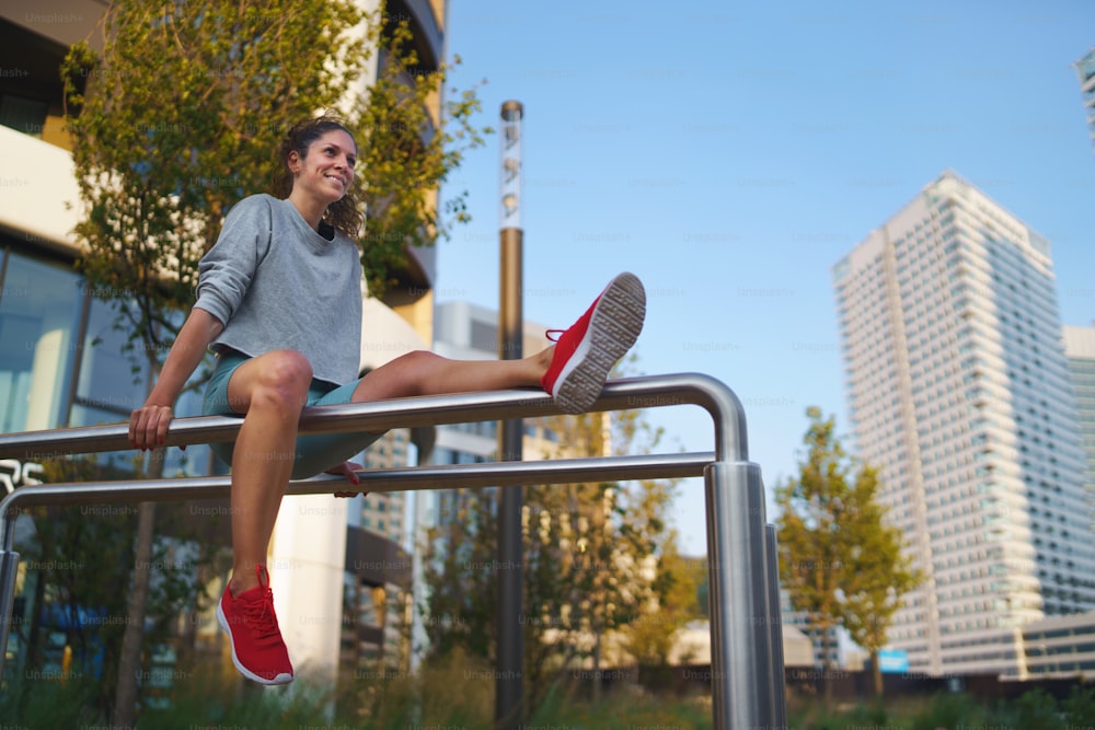 Mujer adulta media feliz haciendo ejercicio en barras paralelas al aire libre en la ciudad, concepto de estilo de vida saludable.