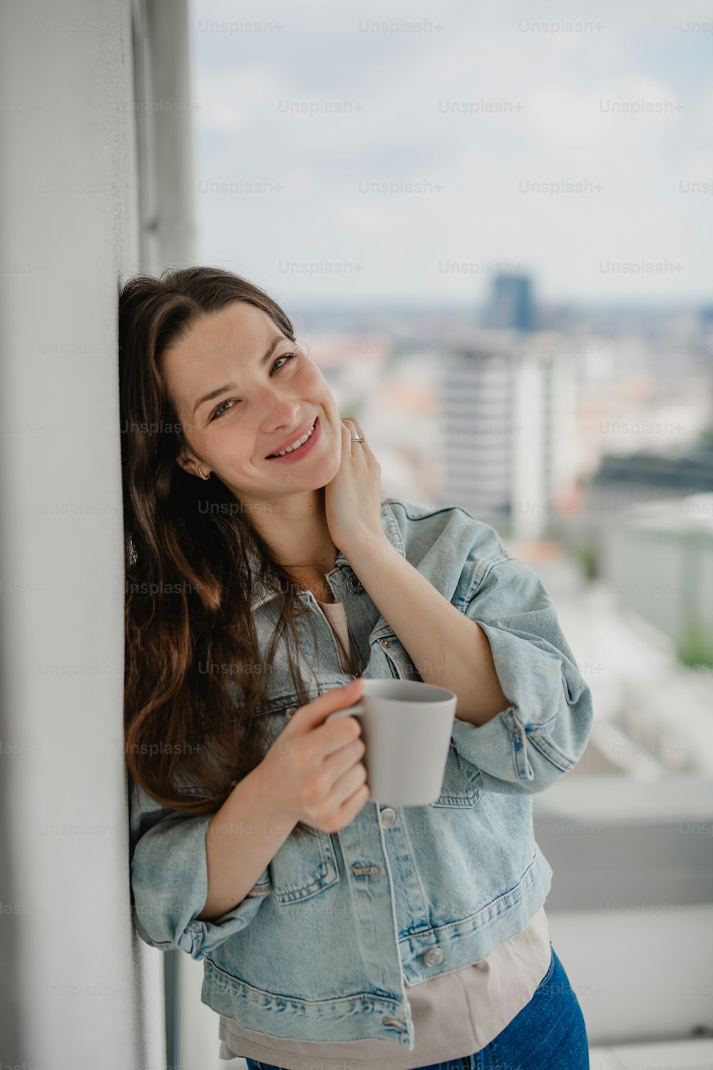Portrait d’une jeune femme caucasienne avec un café à l’extérieur sur le balcon, regardant la caméra.
