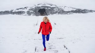 High angle view of an active senior woman outdoors in snowy winter, running.