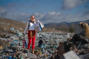 Modische moderne Frau auf Mülldeponie, Konsum versus Umweltverschmutzung Konzept.