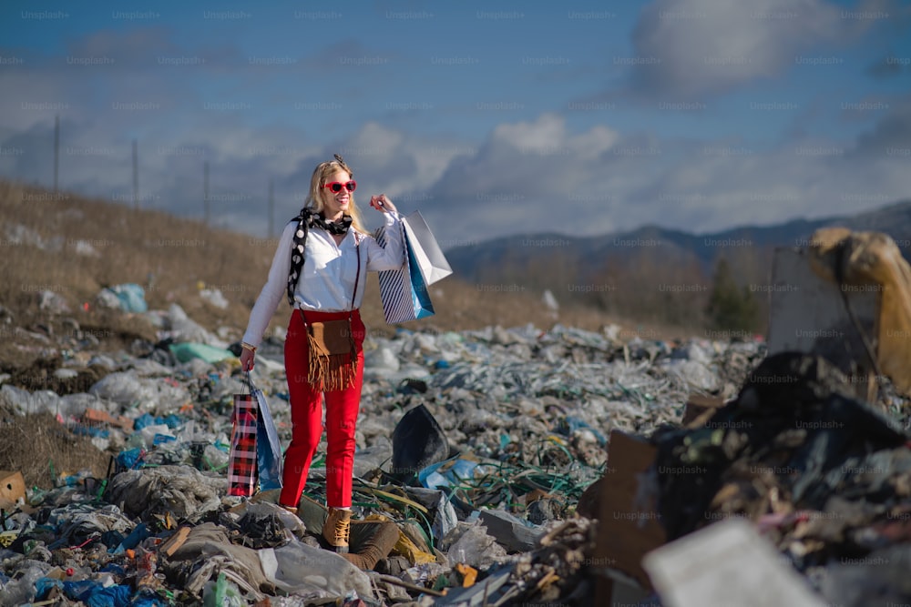 Modische moderne Frau auf Mülldeponie, Konsum versus Umweltverschmutzung Konzept.