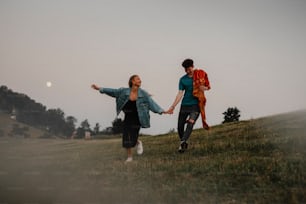 Vista frontal de una pareja joven que camina en la naturaleza al atardecer en el campo, tomados de la mano y corriendo.