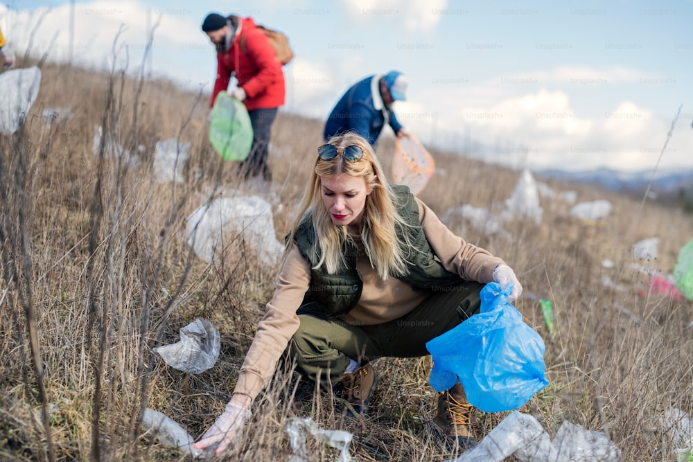 Group of activists picking up litter in nature, environmental pollution and plogging concept.