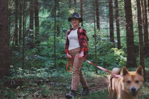 夏の自然の中で森の屋外を散歩する犬を連れた若い女性の側面図。