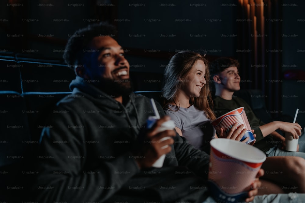 Ein fröhliches junges Paar mit Popcorn im Kino im Gespräch.