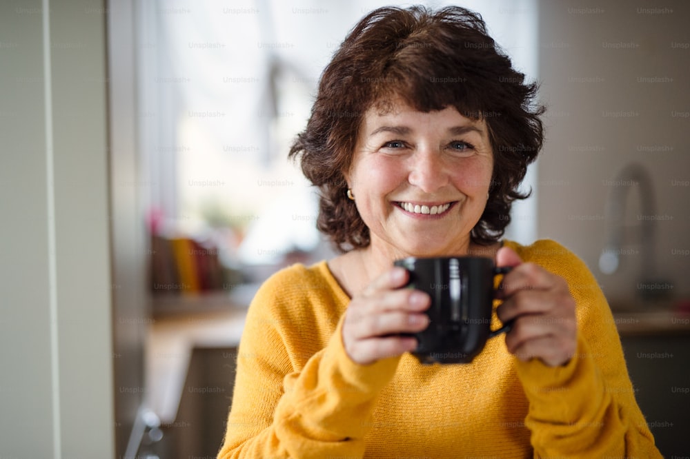 Portrait of senior woman with cup of coffee at home, relaxing.