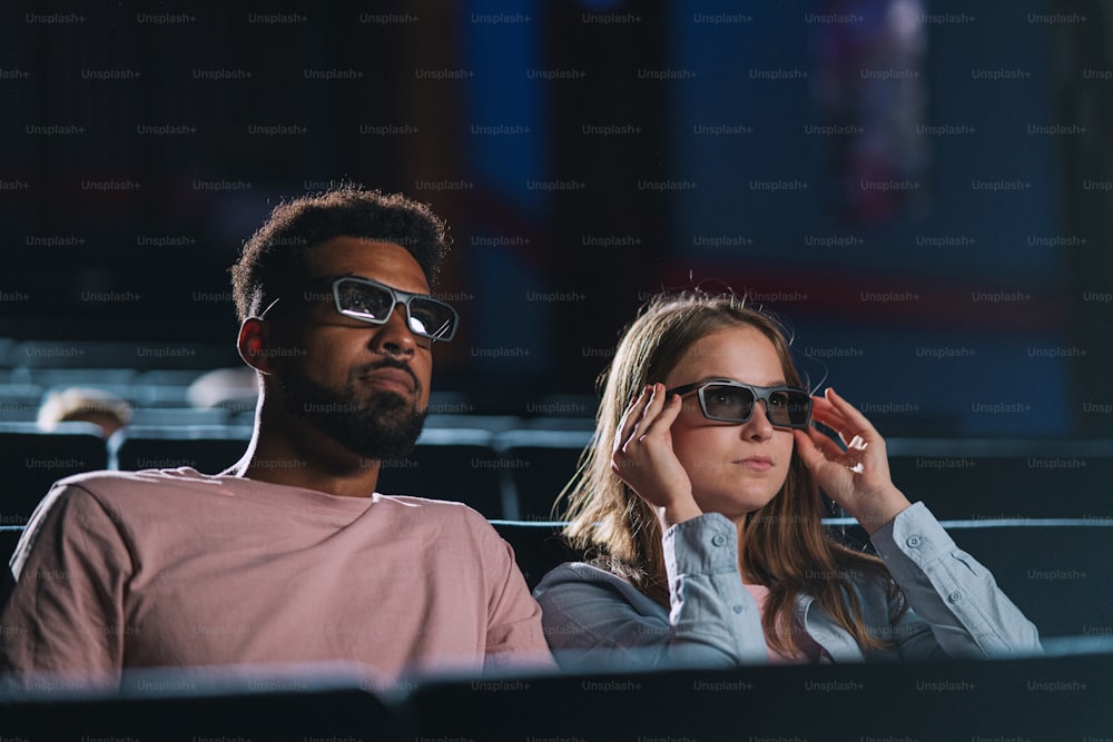 A cheerful young couple with 3d glasses in the cinema, watching film.