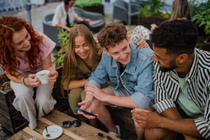 Eine Gruppe glücklicher junger Leute, die auf einem Städtetrip im Café sitzen und sich unterhalten.