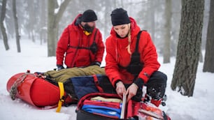 I paramedici del soccorso alpino intervengono all'aperto in inverno nel bosco, il ferito è in barella.