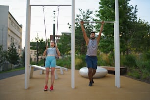 Un uomo e una donna coppia amici che fanno esercizio all'aperto nel parco di allenamento della città