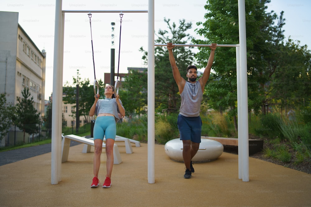 A man and woman couple friends doing exercise outdoors in city workout park