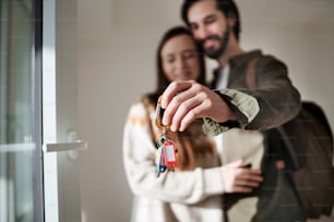 Happy young couple with keys moving in new flat, new home and relocation concept.