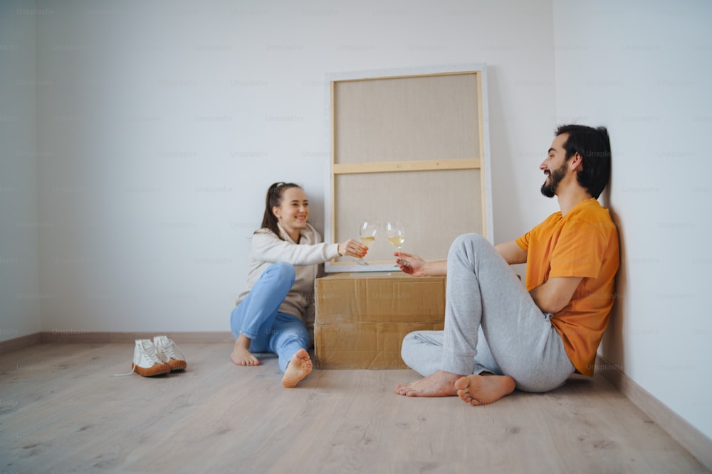 Happy young couple with boxes and wine moving in new flat, new home and relocation concept.