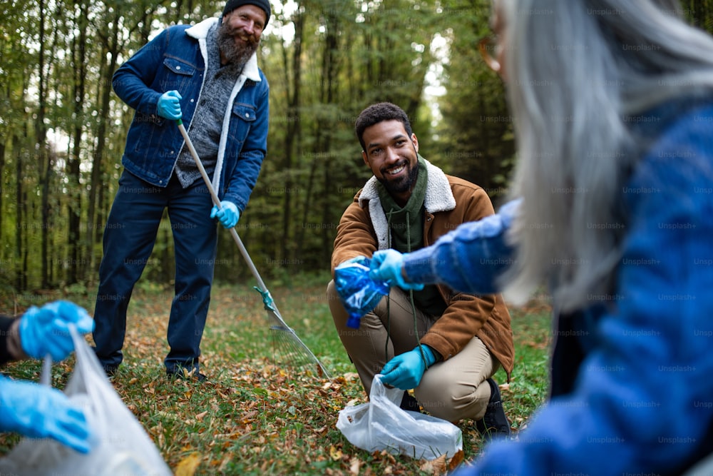 Un grupo diverso de voluntarios felices limpiando el bosque de los desechos, concepto de servicio comunitario.