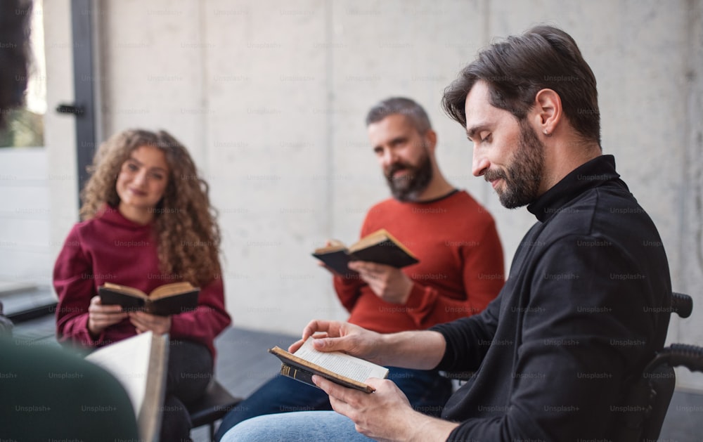 Homens e mulheres sentados em círculo lendo livros bíblicos durante a terapia de grupo.