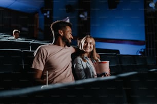 A cheerful young couple in love in the cinema, watching film.