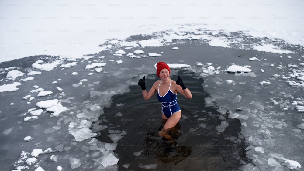 冬の屋外で水着を着たアクティブなシニア女性のハイアングルビュー、コールドセラピーのコンセプト。