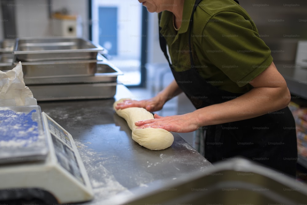 An unrecogniozable chef kneading yeast dough indoors in restaurant kitchen.