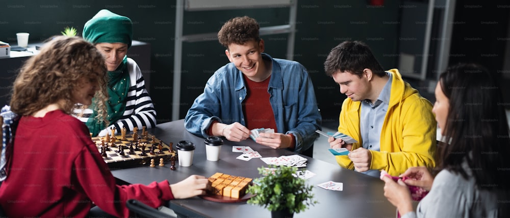 Gruppe glücklicher Menschen, die Karten und Brettspiele im Gemeindezentrum spielen, Inklusivität der behinderten Person.