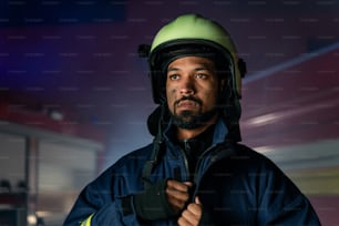 A portrait of dirty firefighter man on duty with fire truck in background at night.