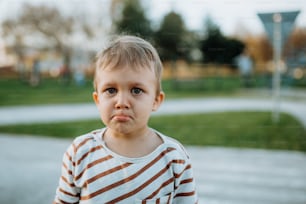Um garotinho triste chorando do lado de fora no parque