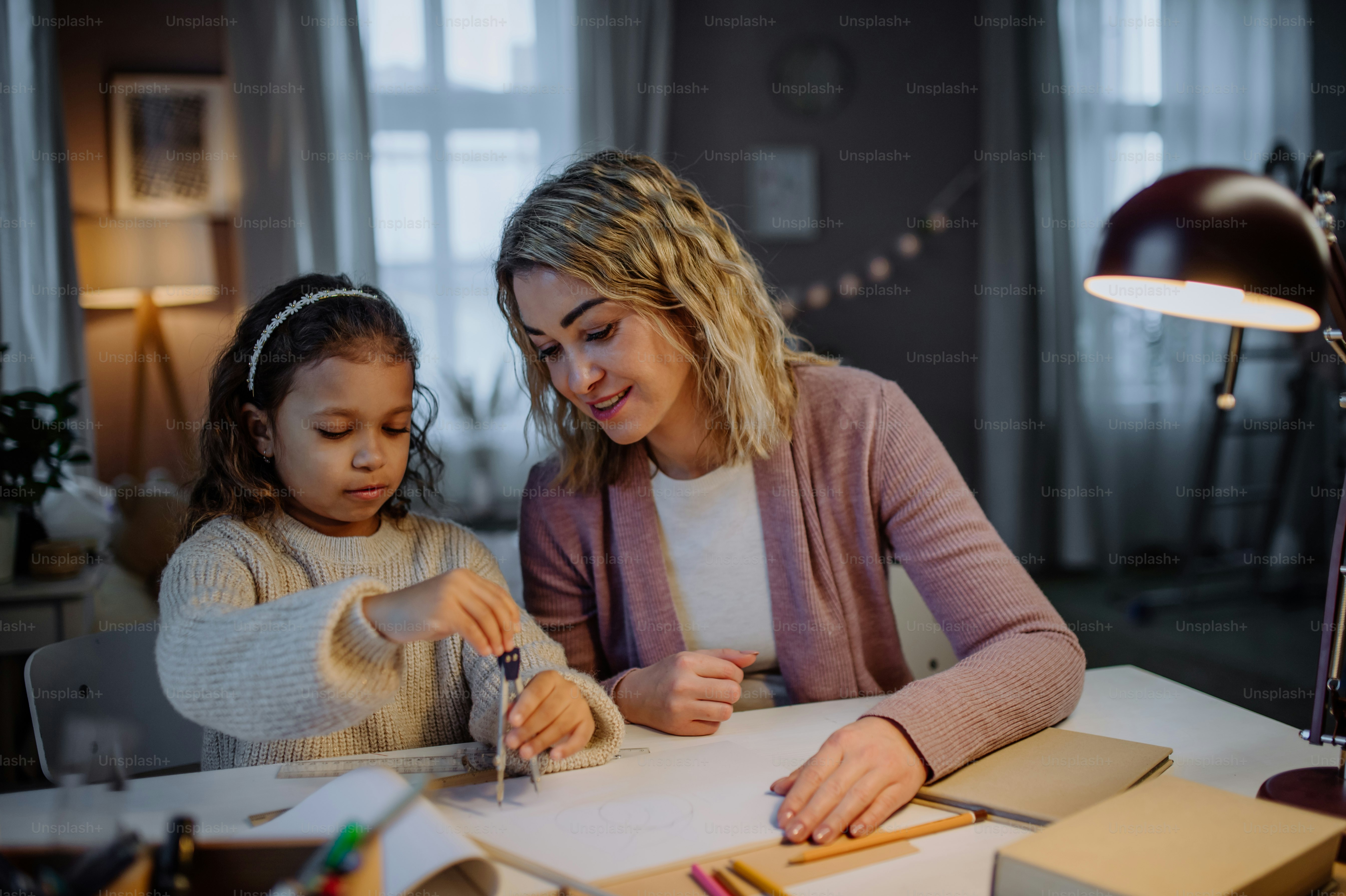 Uma mãe ajudando a filha com a lição de casa, desenhando um círculo com comasses à noite em casa.