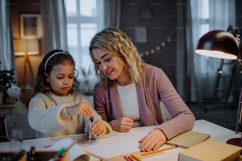 A mother helping her daughter with homework, drawing a circle with comasses in evening at home.