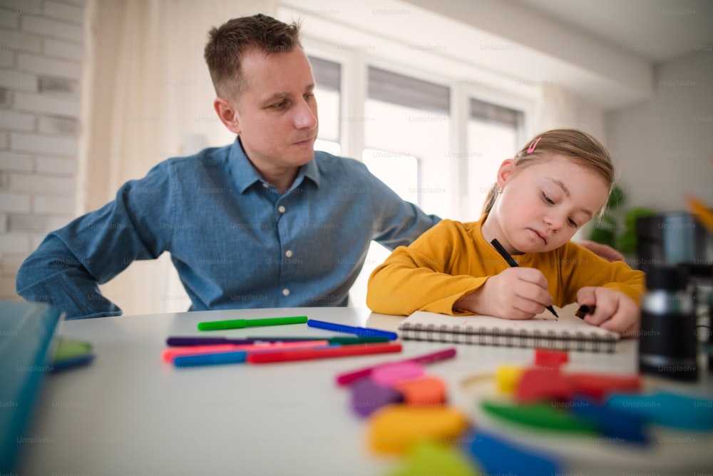 A father with his little daughter with Down syndrome learning at home.