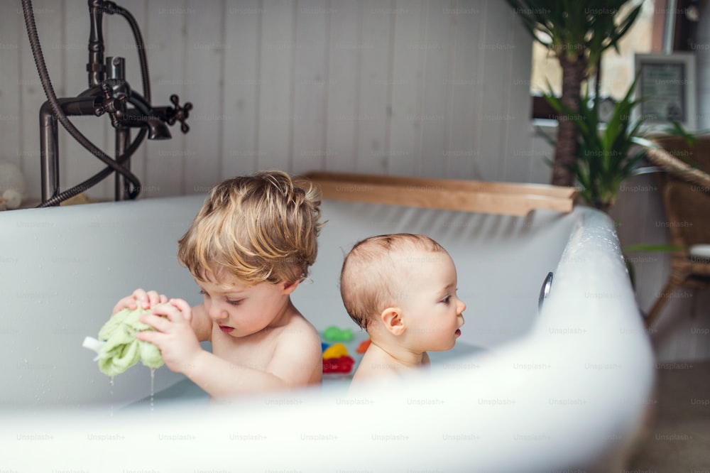 Two happy toddler children having a bath in the bathroom at home.