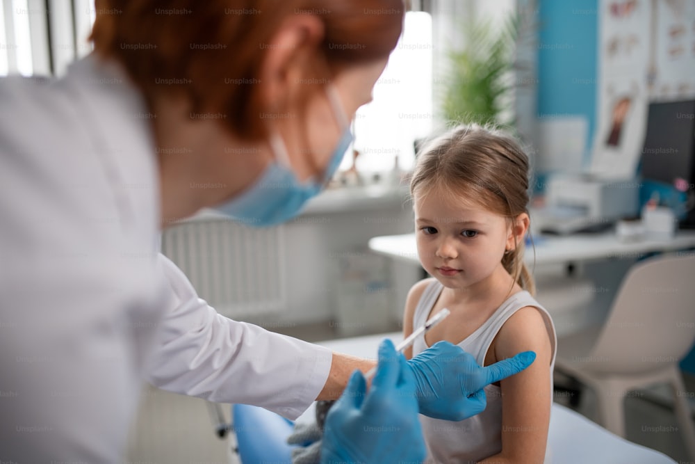 A worried little girl getting vaccinated in doctor's office.