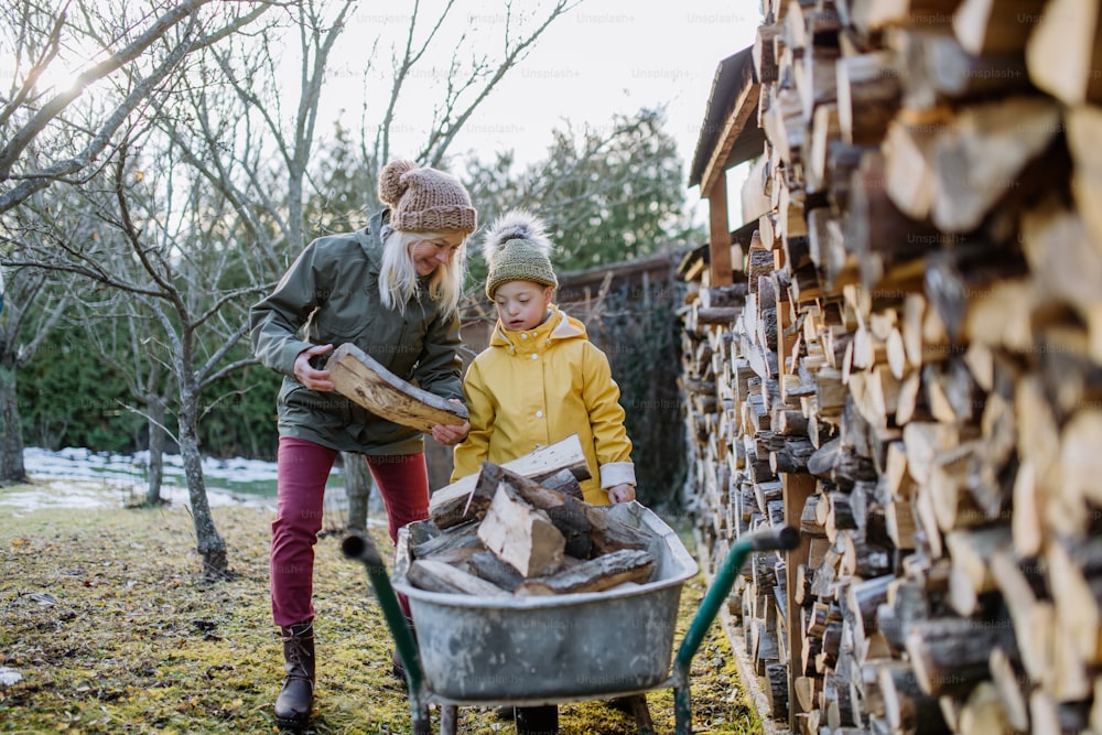 A boy with Down syndrome working in garden in winter with his grandmother.