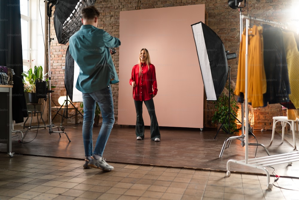 Un joven fotógrafo tomando fotos de la modelo, detrás del escenario de la sesión de fotos en el estudio.